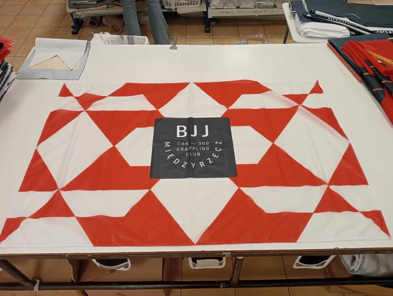 Biało-czerwona flaga klubu z logo BJJ Międzyrzecz