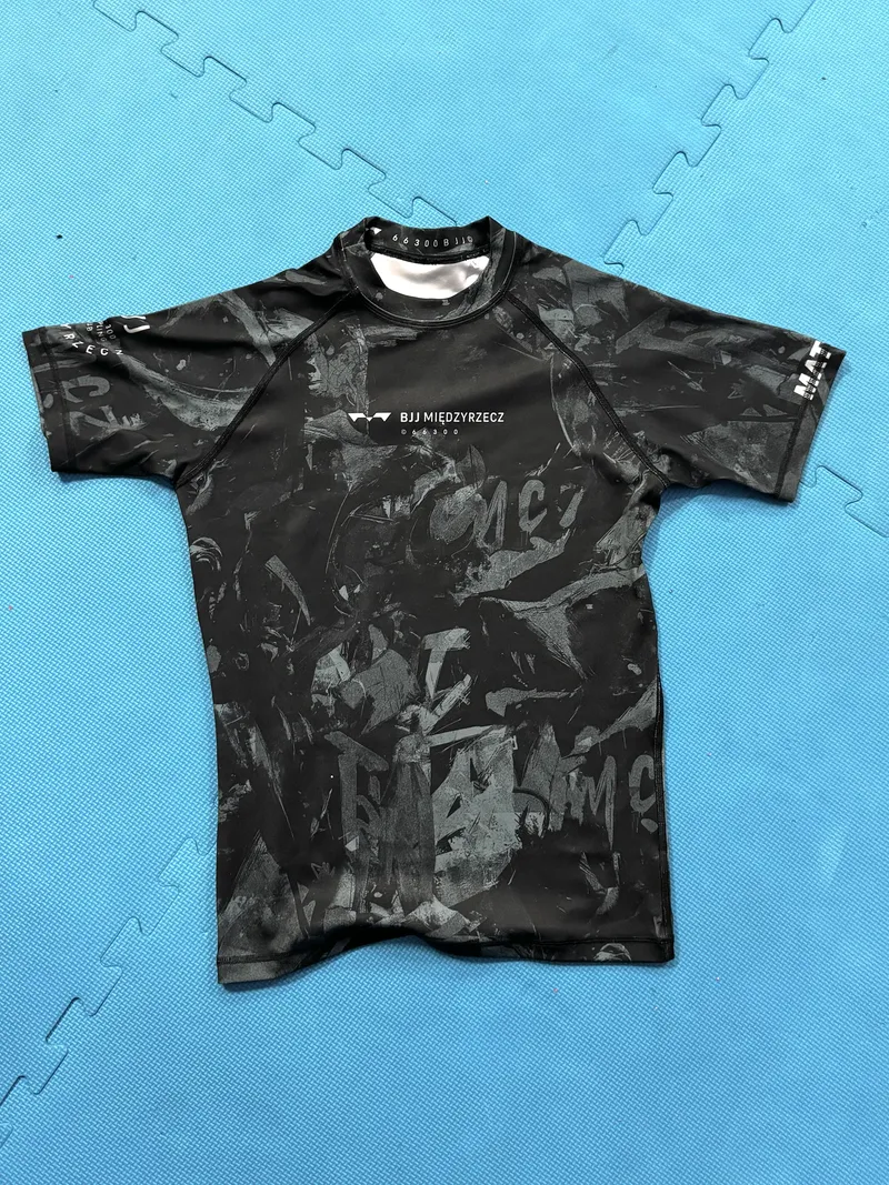 Czarny rashguard z logo BJJ Międzyrzecz na macie