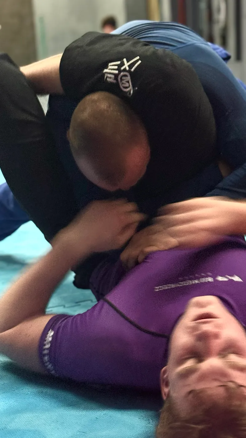 Sparing w parterze, zawodnik w fioletowym rashguardzie