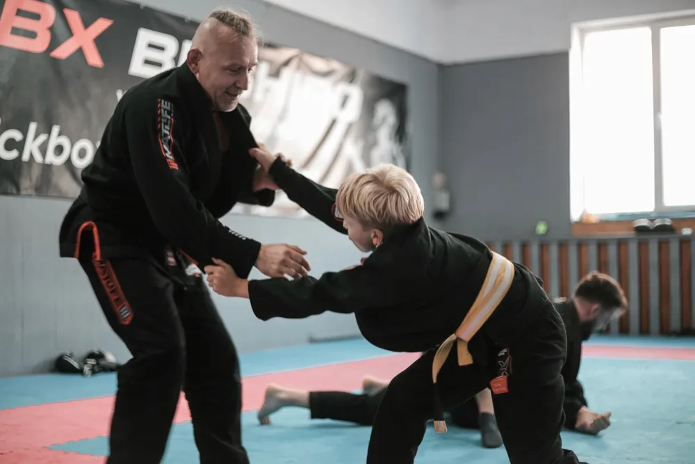Trener prowadzi trening brazylijskiego jiu-jitsu z młodym zawodnikiem
