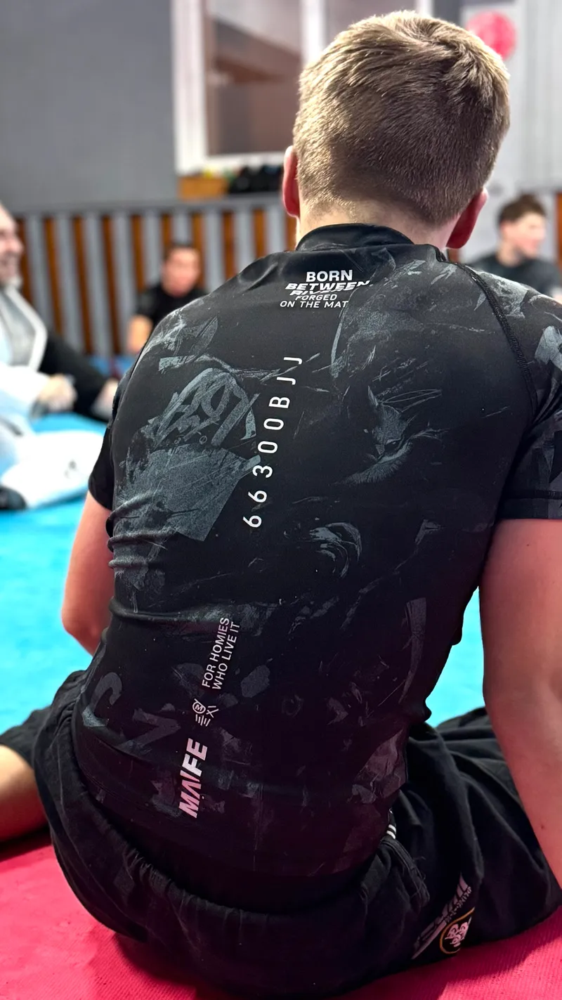 Zawodnik w czarnym rashguardzie klubu z napisem 66300BJJ na plecach
